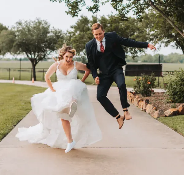 Creative Wedding Photo Near Me Bride and groom jumping playfully on a path during their Houston wedding